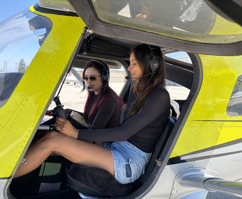 Two friends in headsets in the cockpit of a yellow training airplane before a discovery flight at Van Nuys