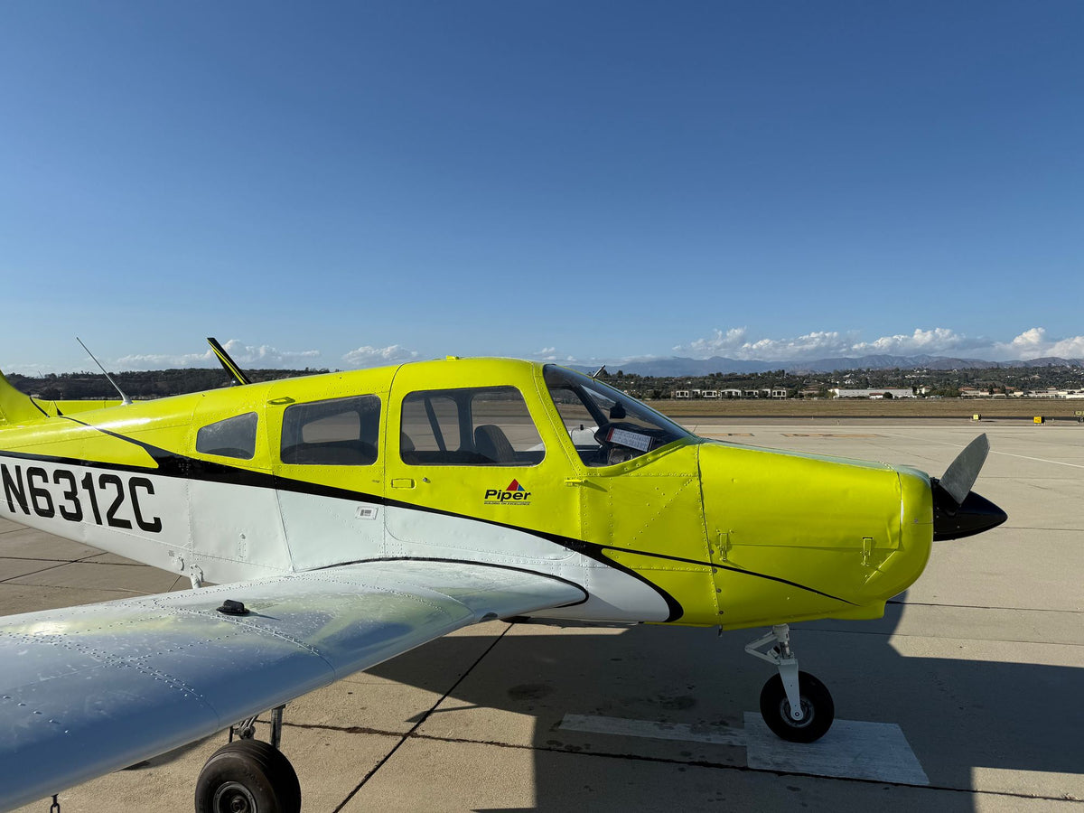 Close side view of yellow and white Piper Warrior N6312C showing the registration, cabin and cowling