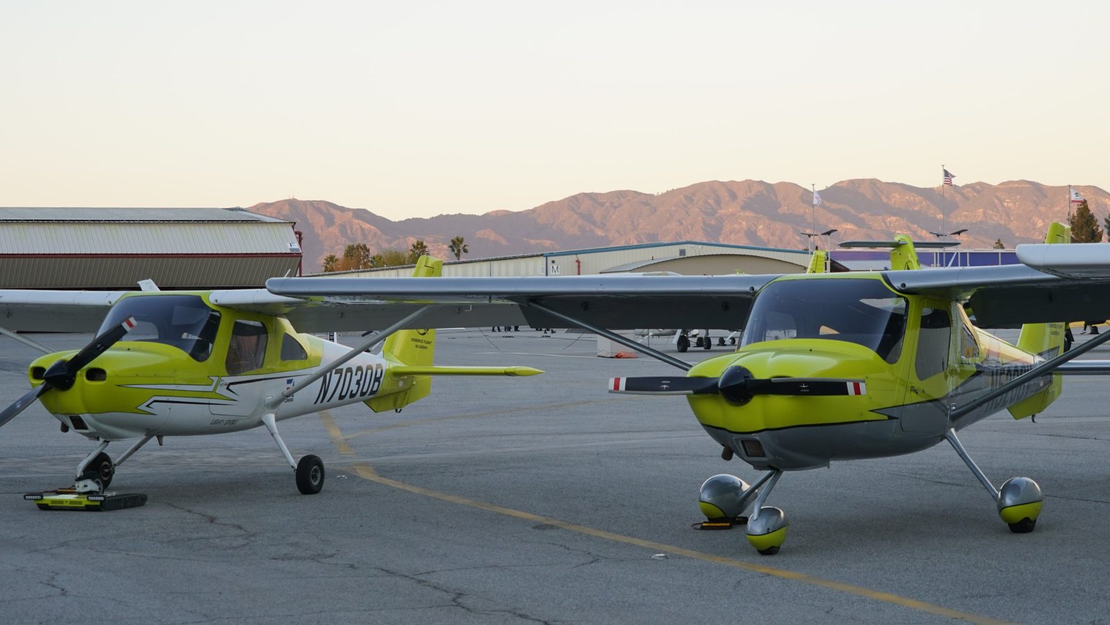 Two yellow Cessna 162 Skycatchers, N7030B nearest, parked on the Van Nuys ramp at sunset