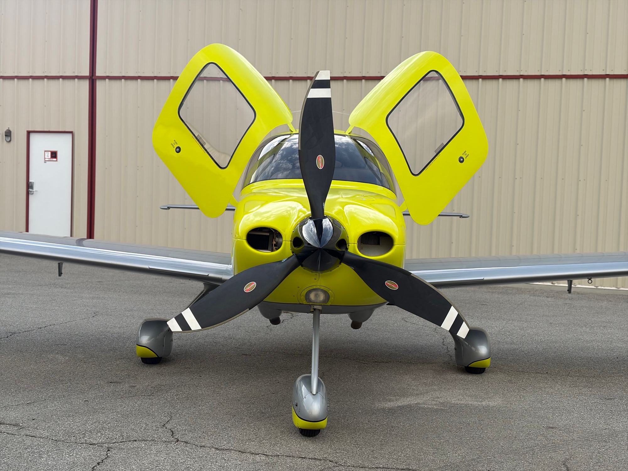 Cirrus SR22 Turbo head-on in front of a hangar with both gull-wing doors raised