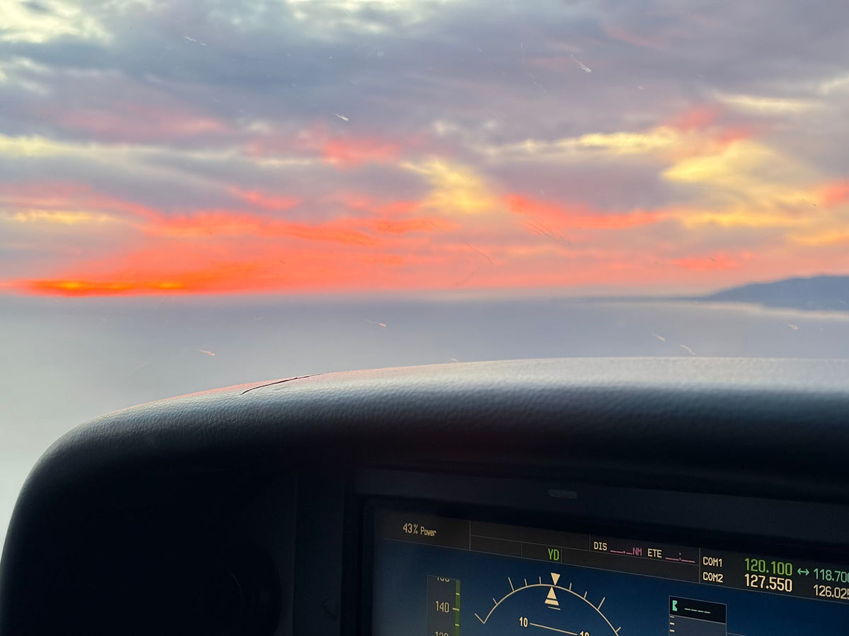 Glass flight display in a training airplane cockpit with the sunset sky ahead