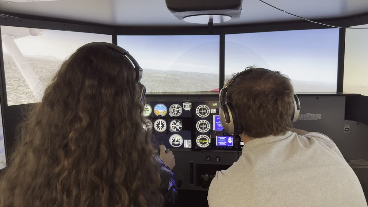 A student and an instructor at the panel of the full-motion simulator with the wraparound view ahead