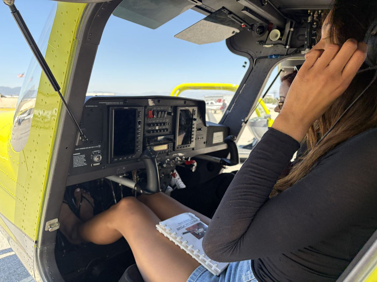 Student pilot in a headset scanning a glass cockpit display during a training flight