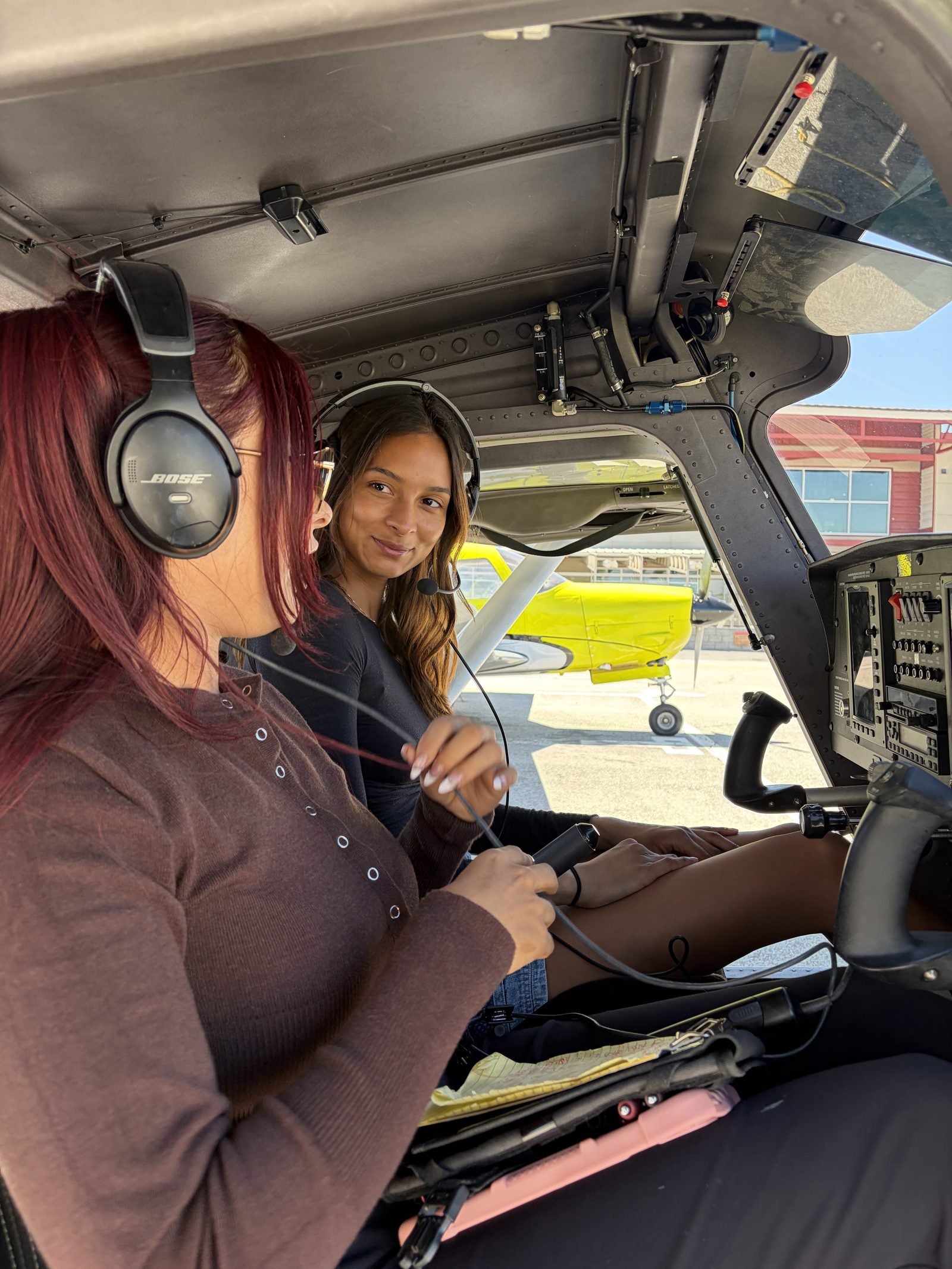 Instructor and student side by side in a training airplane cockpit, both in headsets