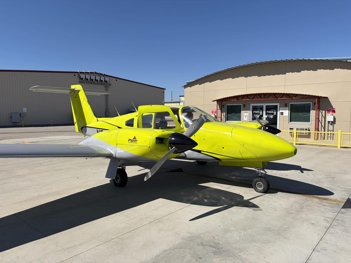 Yellow Piper Seminole twin parked on the sunny ramp outside a hangar office at Van Nuys