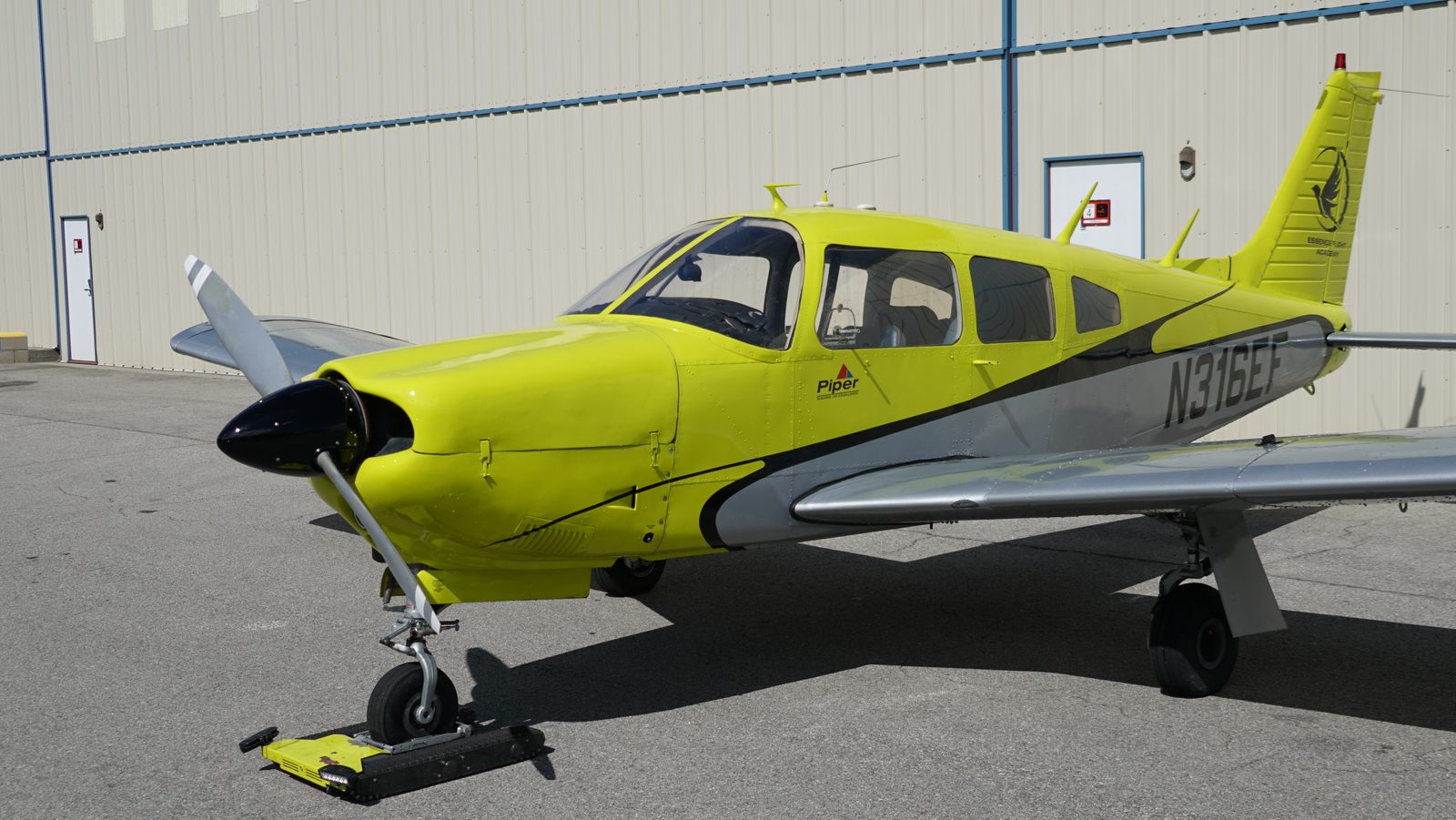 Side profile of a four-seat low-wing Piper trainer on the ramp
