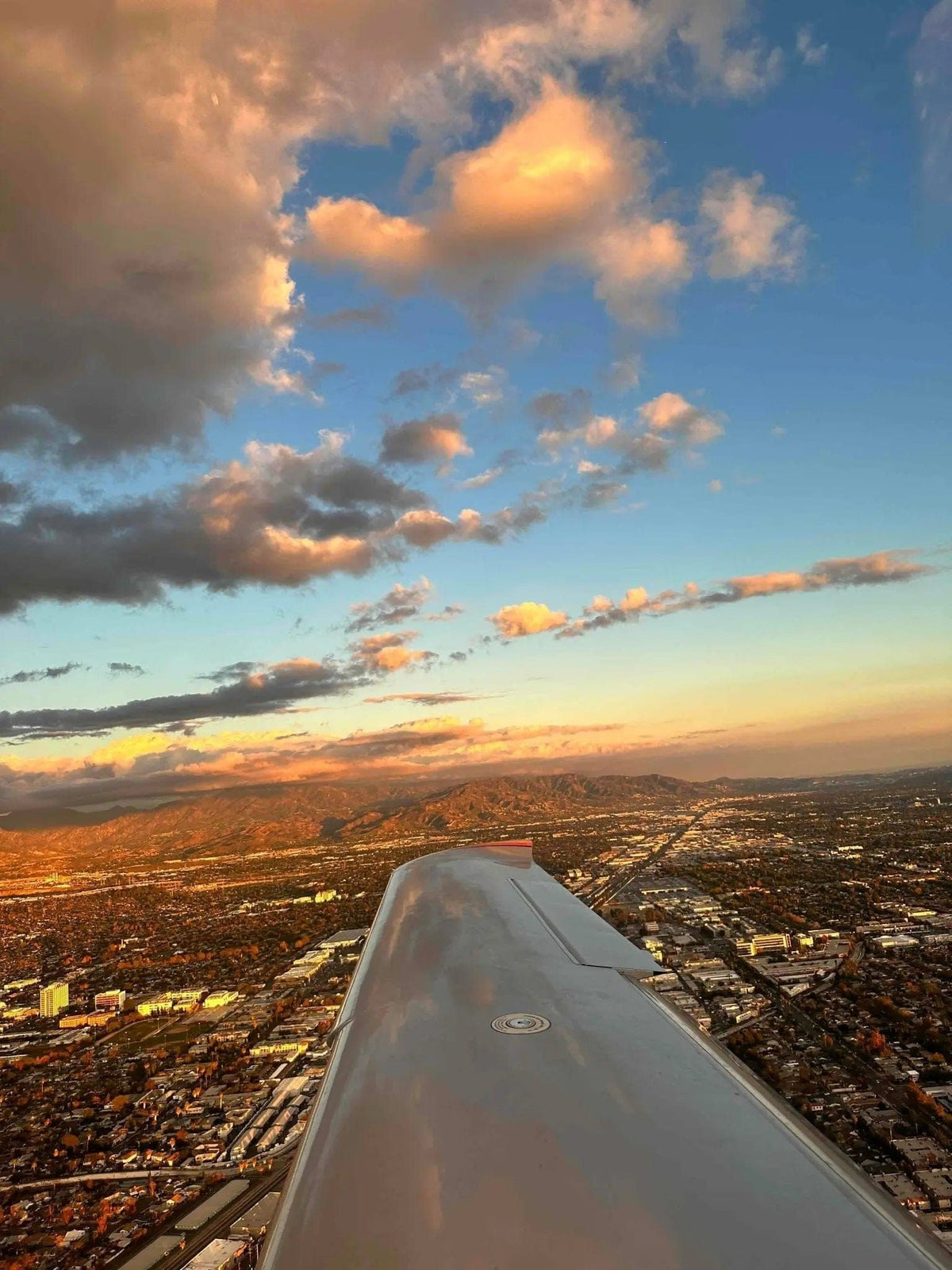 Wing of a training airplane over Los Angeles as the city lights come on at dusk, seen on a night discovery flight from Van Nuys