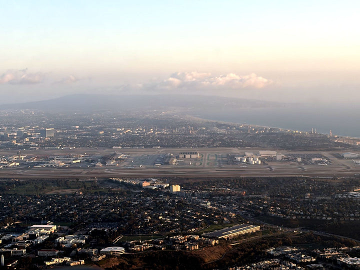 Los Angeles International Airport and its runways seen from a small airplane passing north of the airport, with Santa Monica Bay and the Palos Verdes Peninsula on the horizon