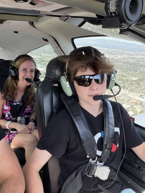 Young pilot wearing a headset, smiling at the controls during a flight experience in Los Angeles